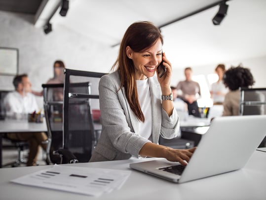 Woman agent talking on cellphone while on laptop